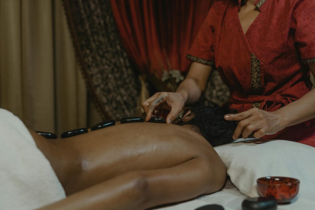 Person receiving a relaxing hot stone massage in a serene spa setting for ultimate relaxation.